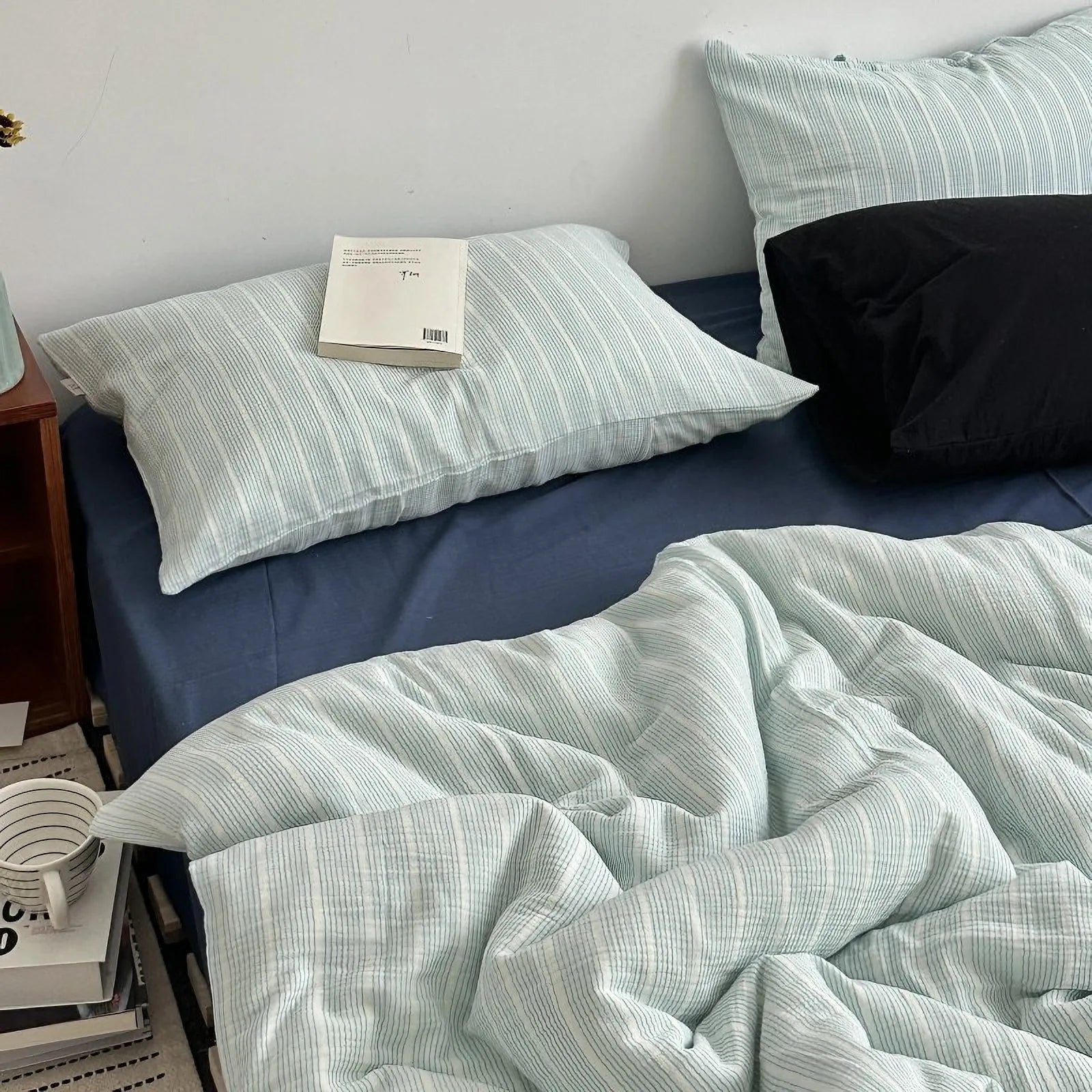 Textured cyan and white pinstripe washed cotton bedding set on a bed with a book on the pillow - RoomDen.