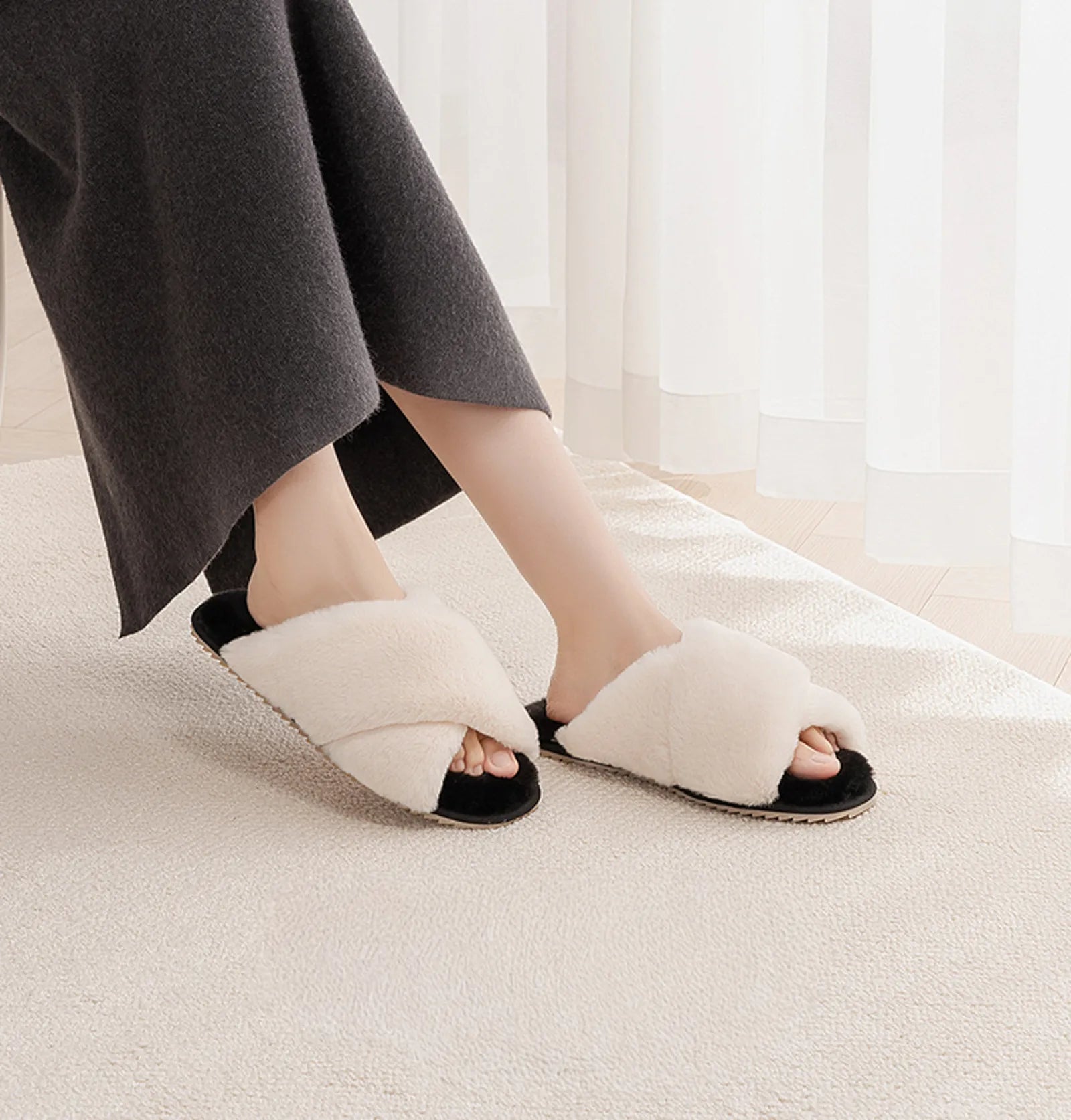 Woman wearing White and Black cross-band faux fur slippers sitting with legs crossed - RoomDen