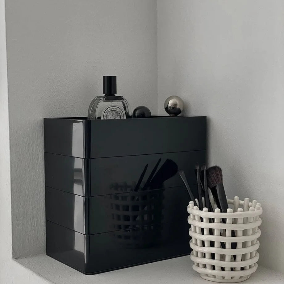 Close-up of the Black rotating makeup organizer next to a white woven brush holder.