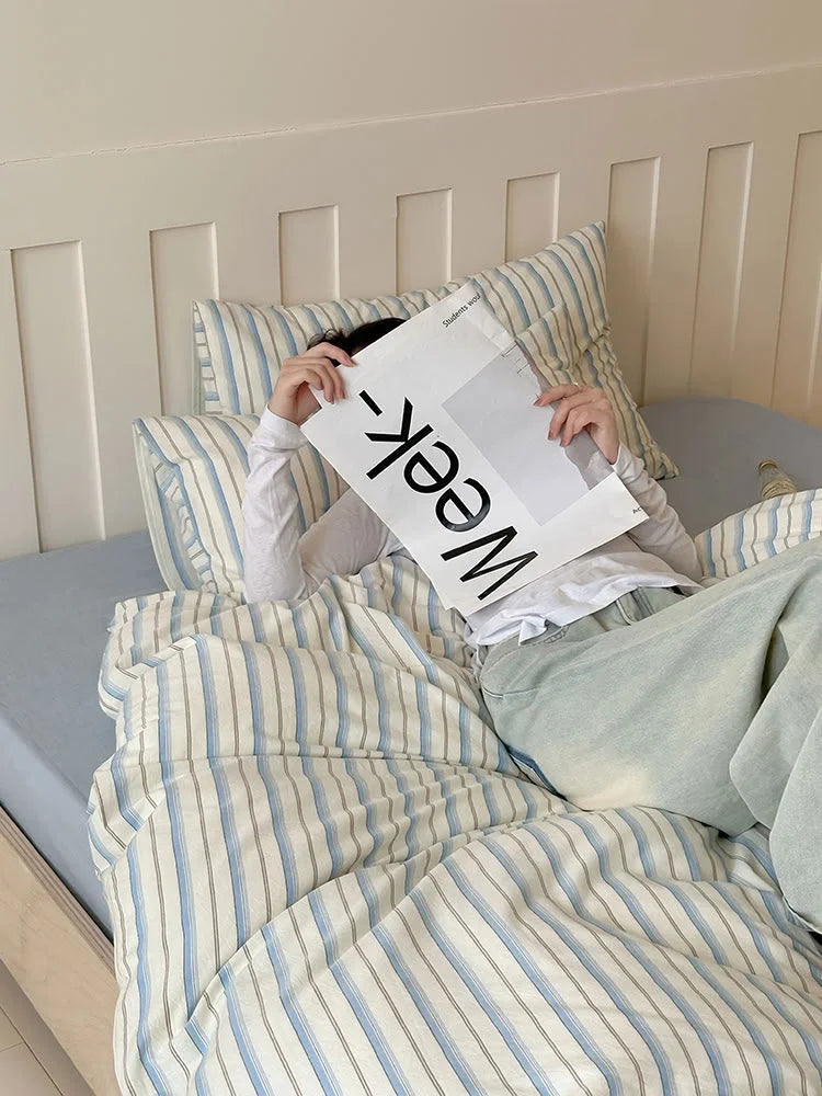 Lifestyle shot of someone relaxing with the Blue Pinstripe Washed Cotton Bedding Set. - RoomDen