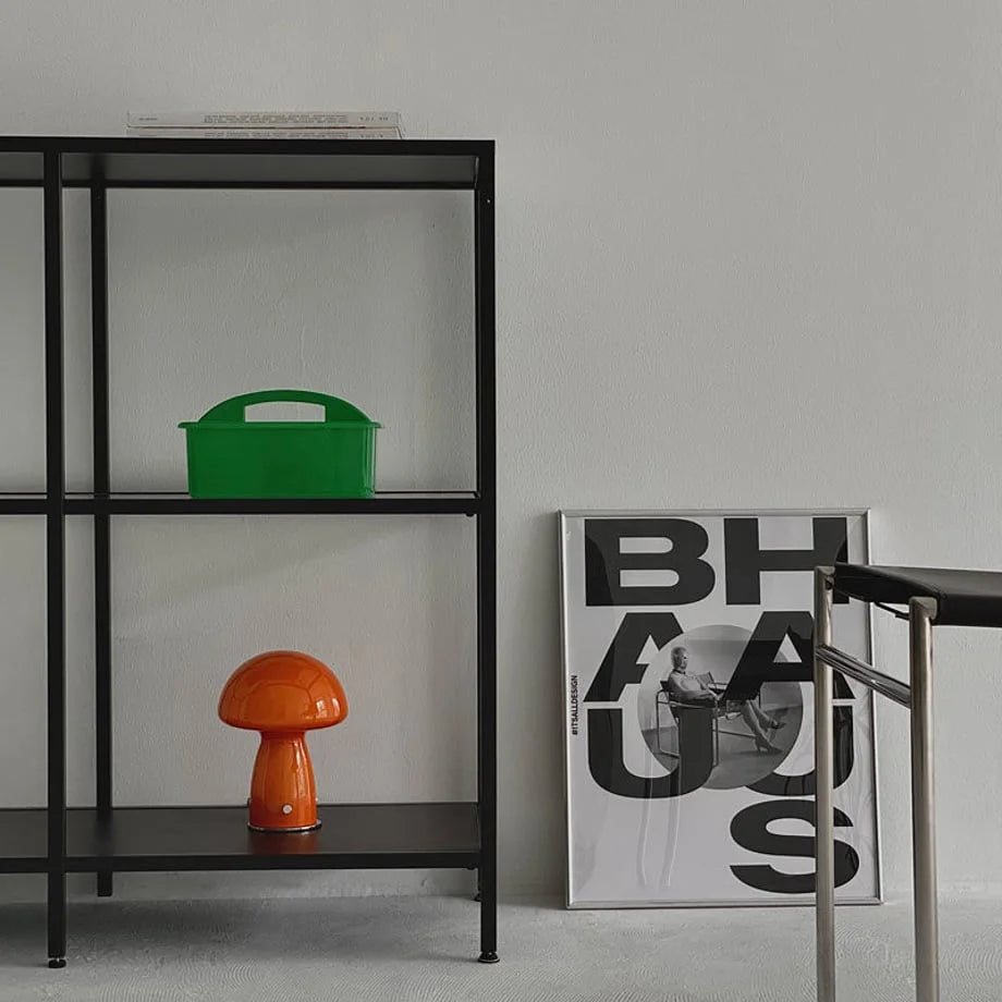 Lifestyle scene with a green organizer caddy and an orange mushroom lamp on a shelf next to a Bauhaus poster. - RoomDen