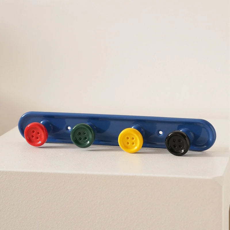 Blue 4-hook button ceramic wall rack with colorful buttons on a white surface. - RoomDen