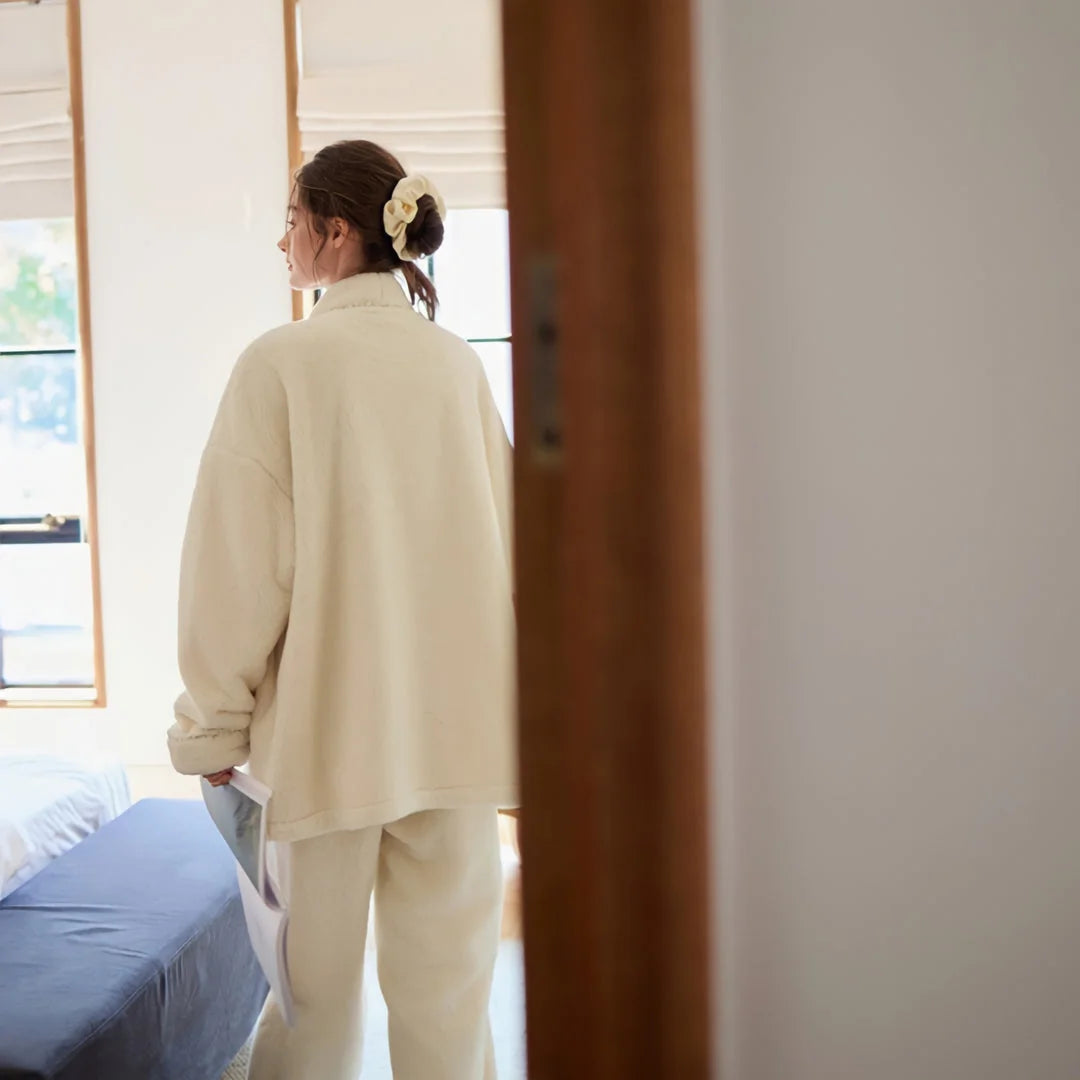 Back view of the model wearing the oversized cream fleece pajama top, walking into a bedroom - RoomDen.