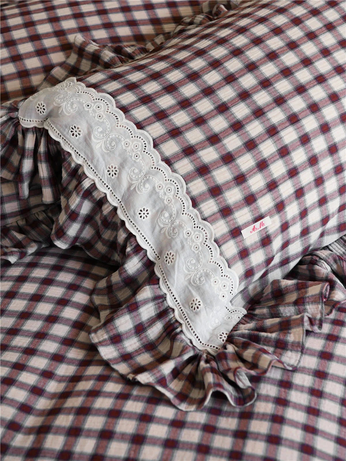 Macro shot of the embroidered white lace detail on the Brown Gingham pillow sham.