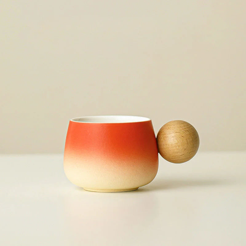 A clear studio shot of the Sunset Orange gradient ceramic mug with its spherical wooden handle. - RoomDen
