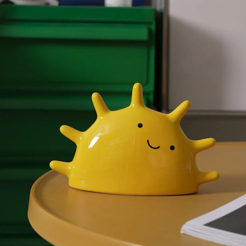 Front view of the Sunny Yellow Matte Ceramic Smiling Sun Jewelry Organizer on a yellow table - RoomDen