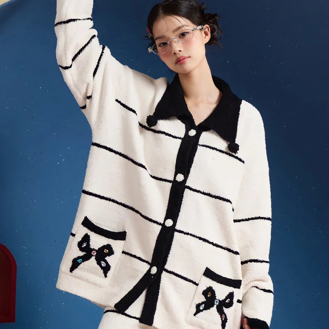 Close-up of the collared top of the white and black striped fleece pajama set, showing the bejeweled bow appliqué on the pocket - RoomDen.