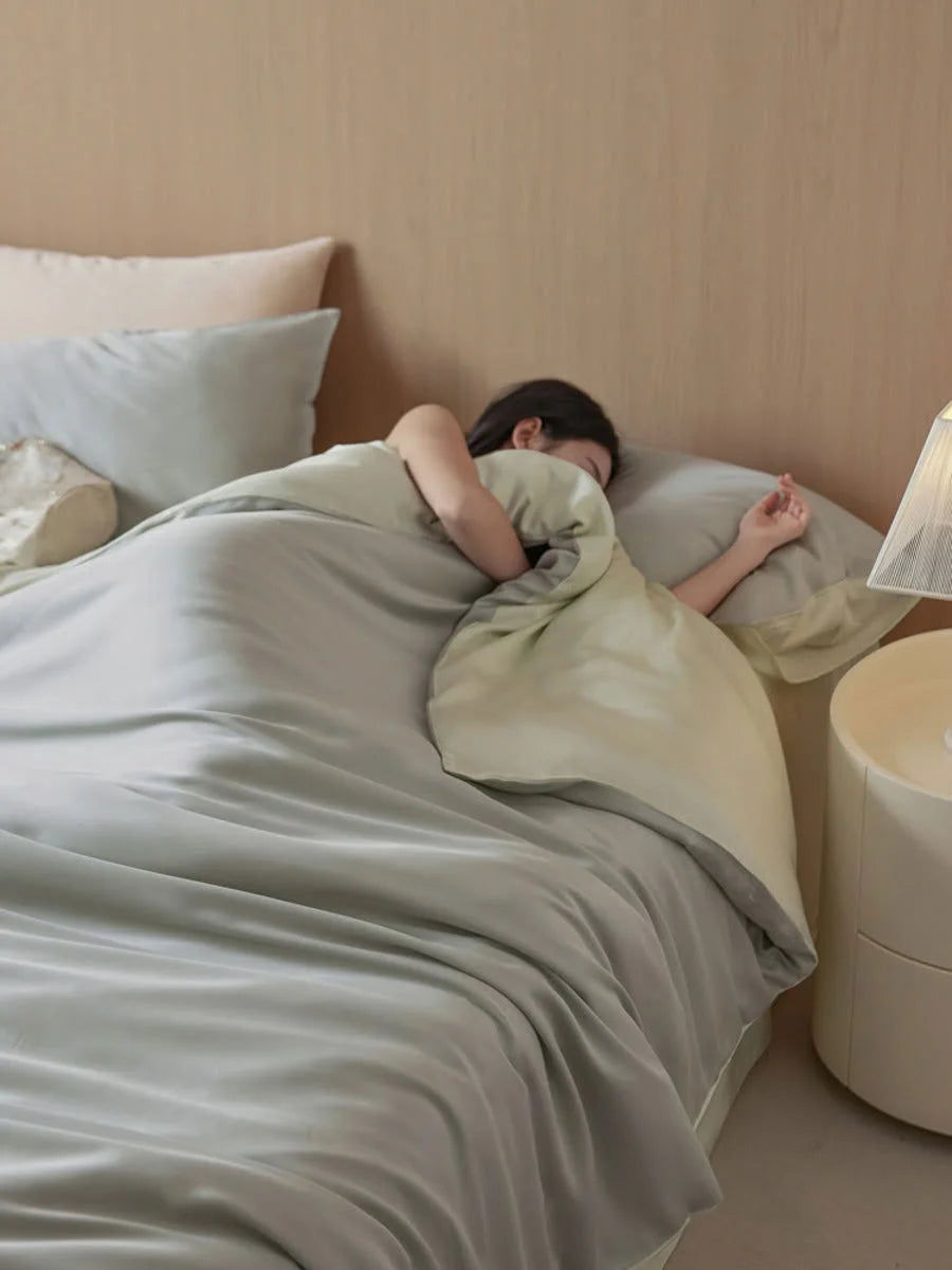 A person sleeping comfortably under the Sage Mist Cooling Tencel duvet cover. - RoomDen