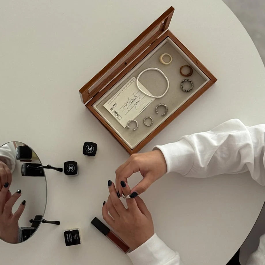Top-down view of a minimalist desk with a wood jewelry box, mirror, and makeup. - RoomDen