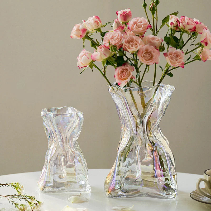 The small and large iridescent Sculptural Crumpled Glass Vases side-by-side, the larger one filled with pink roses. - RoomDen