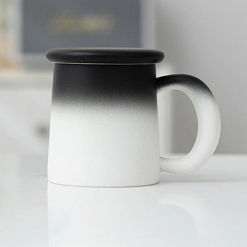 Side view of the Black & White Ombre Frosted Ceramic Mug with lid on a white surface - RoomDen.
