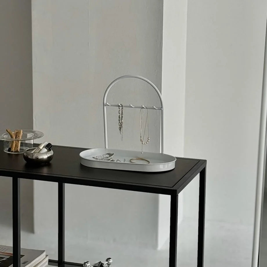 White Sleek Arched Metal Jewelry Organizer on a black console table. - RoomDen