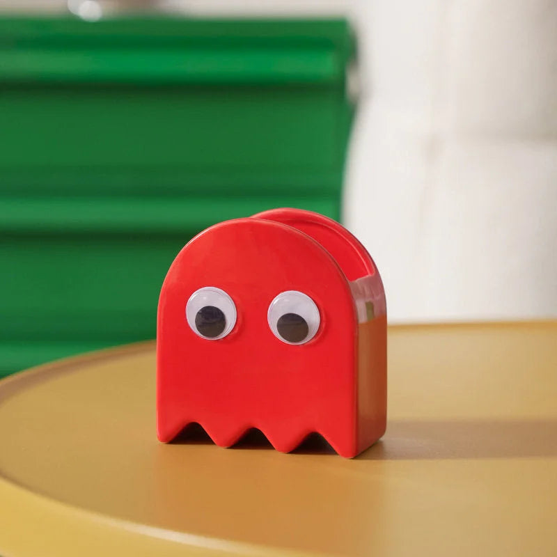 The red Retro Ghost Ceramic Pen Holder on a yellow table with a green background - RoomDen.