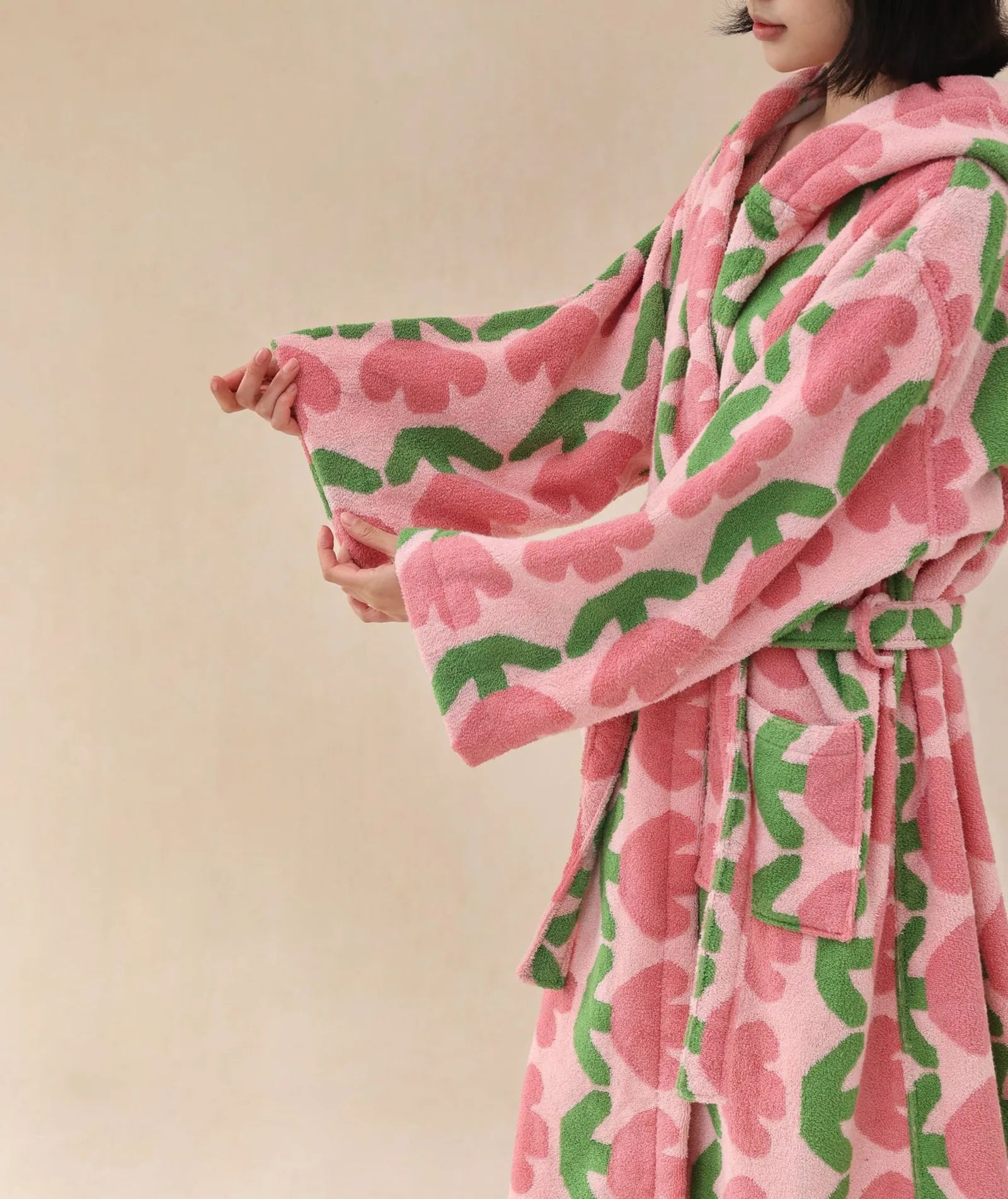 Close up detail of pink floral pattern and green leaves on soft cotton robe sleeve.