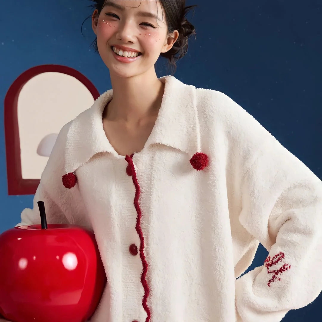 Model in the Cream White fleece pajamas holding a large red apple prop, highlighting the red details.