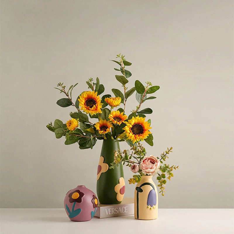 All three vases (green, mauve, beige) displayed with flowers on a white table with a Versace book. - RoomDen