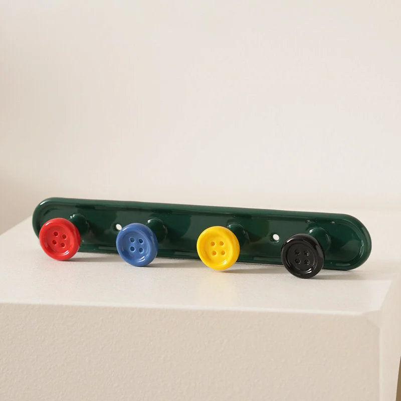 Green 4-hook button ceramic wall rack with colorful buttons on a white surface. - RoomDen