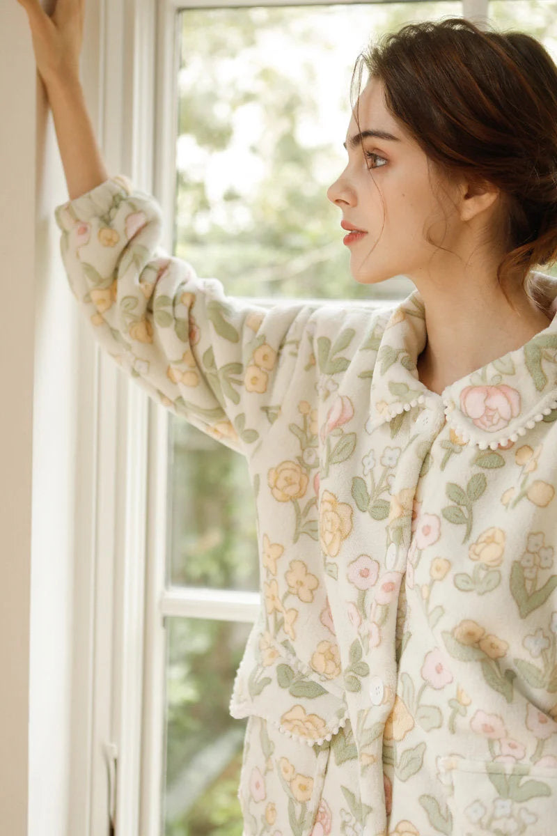 Side view of woman looking out window wearing floral fleece pajamas - RoomDen
