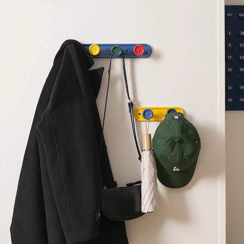 Blue and yellow button wall hook racks used for entryway organization of a coat, bag, and hat. - RoomDen