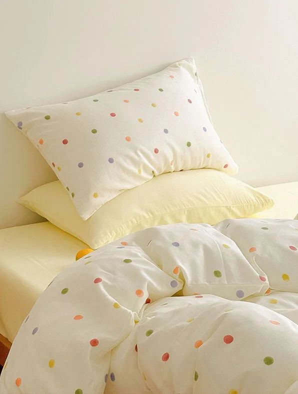 Pillowcases from the Colorful Polka Dot Bedding Set stacked on a pale yellow fitted sheet - RoomDen