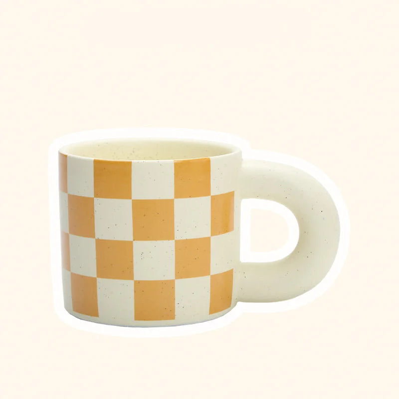 Angled view of the Orange Checkered Ceramic Mug with a Puffy Handle. - RoomDen