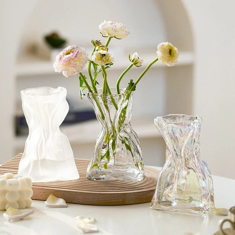 All three vase styles (frosted, clear, iridescent) displayed together on a white table, one holding flowers. - RoomDen