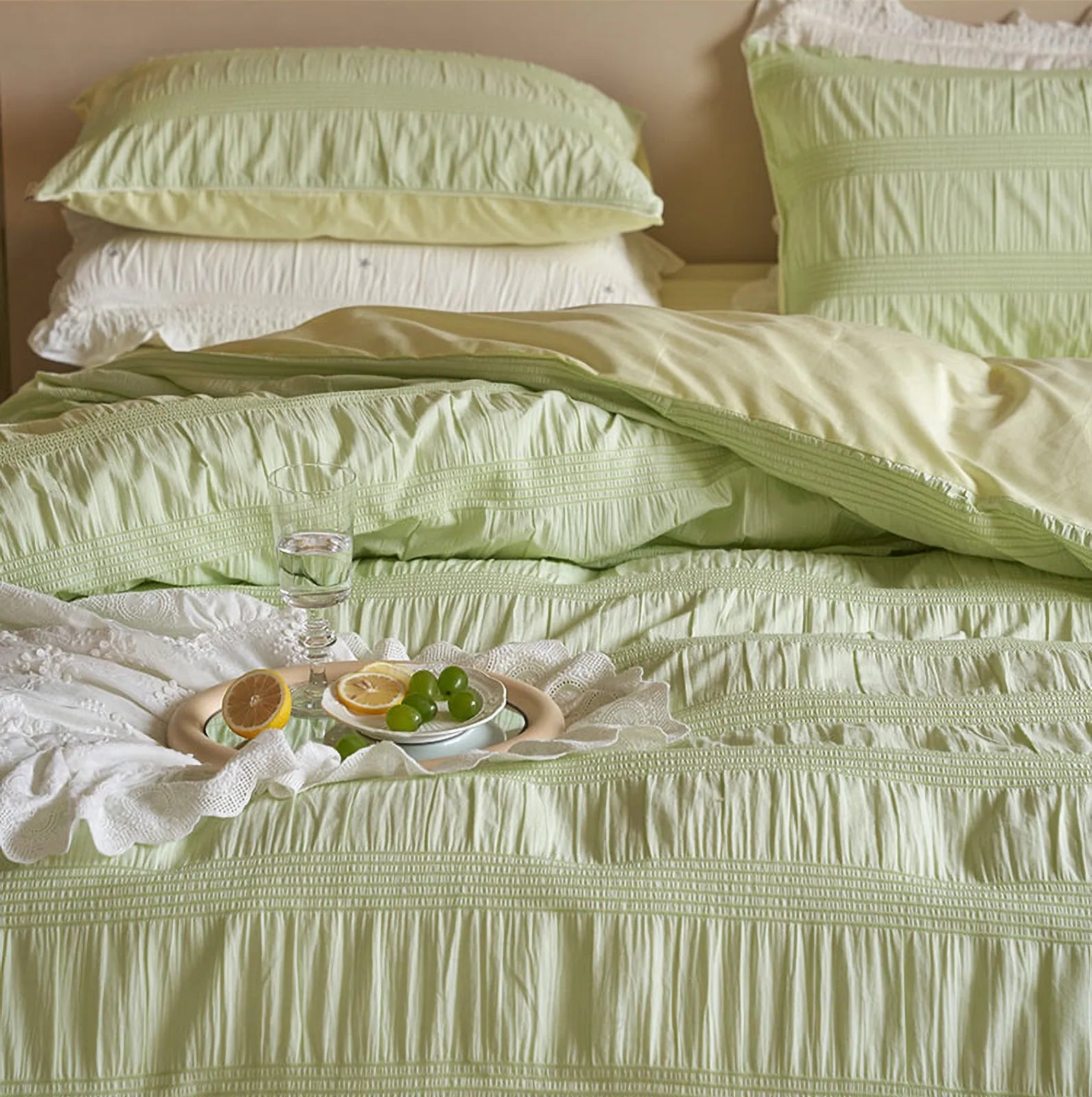A tray with lemon and grapes resting on the Textured Pintuck Bedding Set in Pistachio Green.