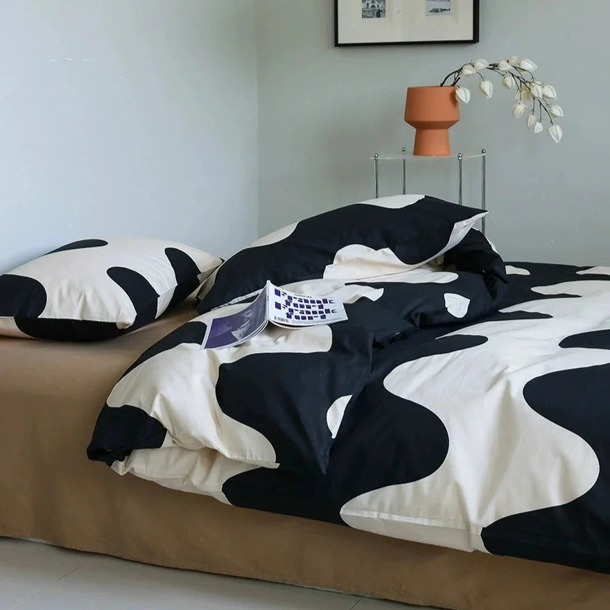 Angled view of the Wavy Abstract Cotton Bedding Set, with a magazine resting on the duvet - RoomDen