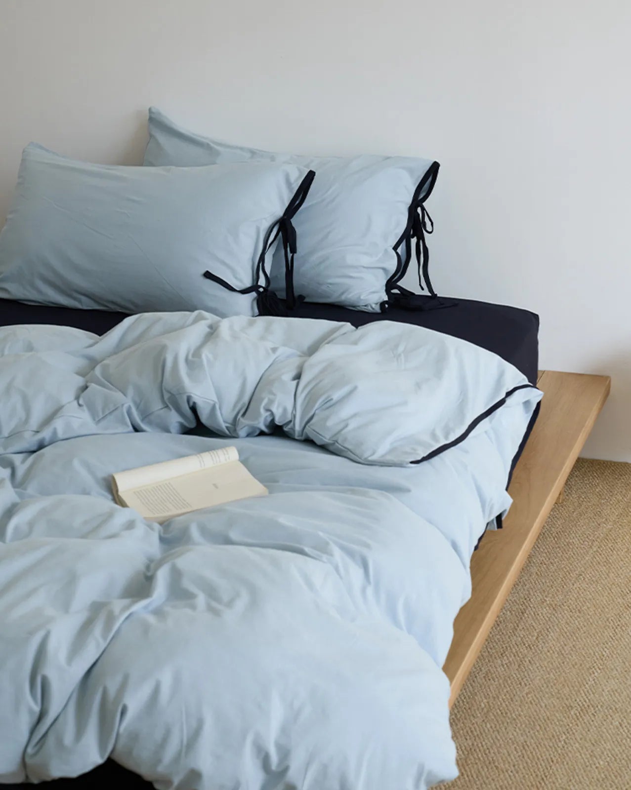 Another angle of the Sky Blue & Black bedding set with a book, showing its relaxing vibe. - RoomDen