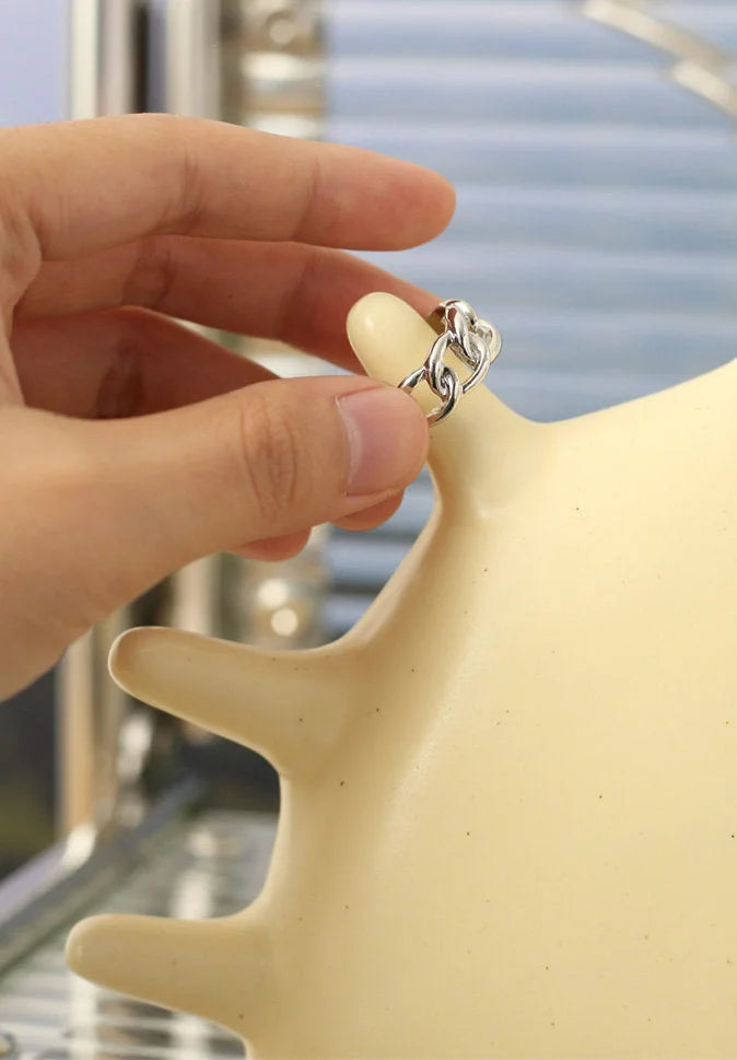 Detail shot of a hand placing a silver chain ring on the Creamy Beige Smiling Sun Jewelry Organizer - RoomDen