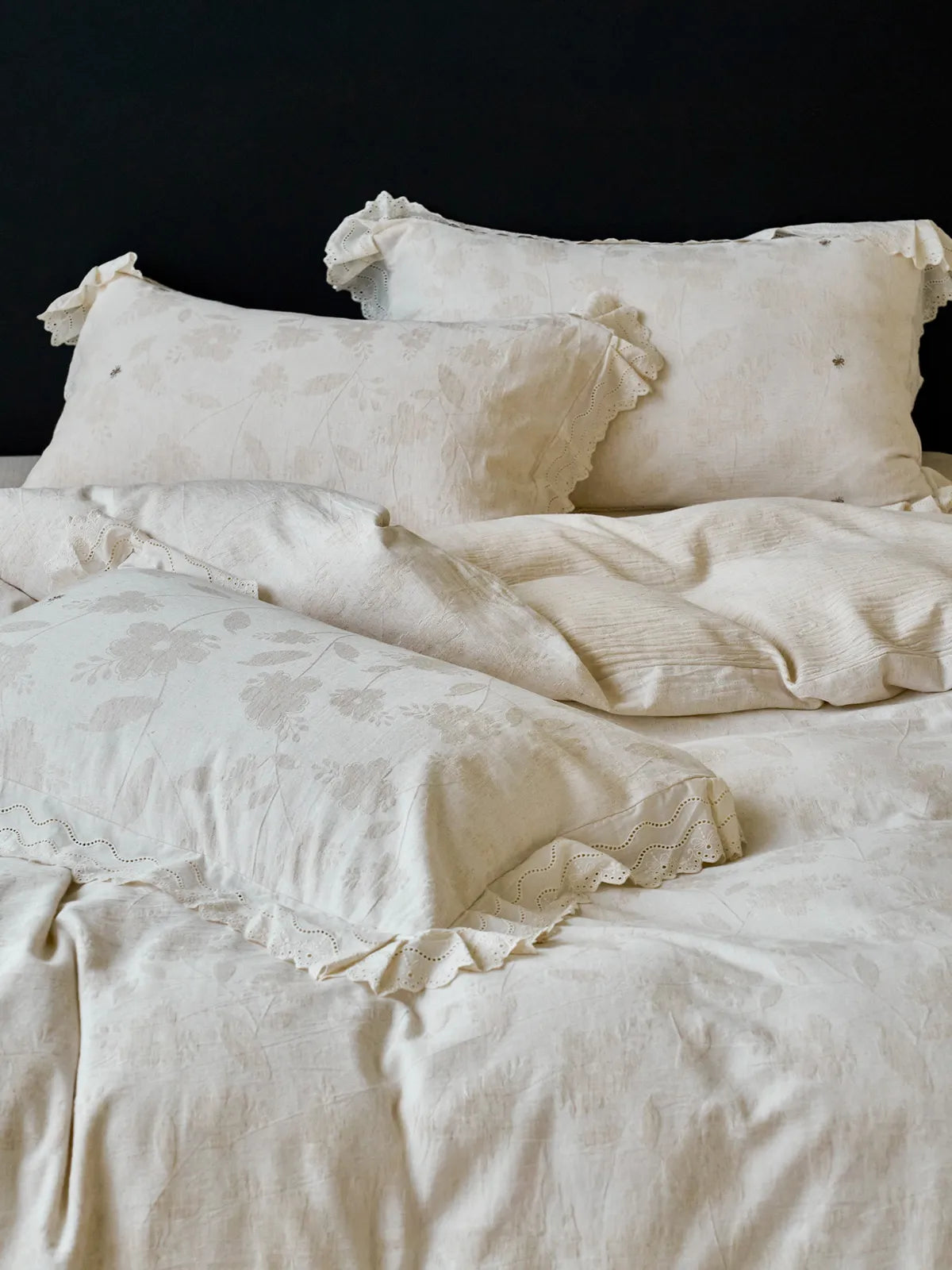 Full bedding set display featuring floral embroidered duvet cover and ruffled pillows in warm light RoomDen.