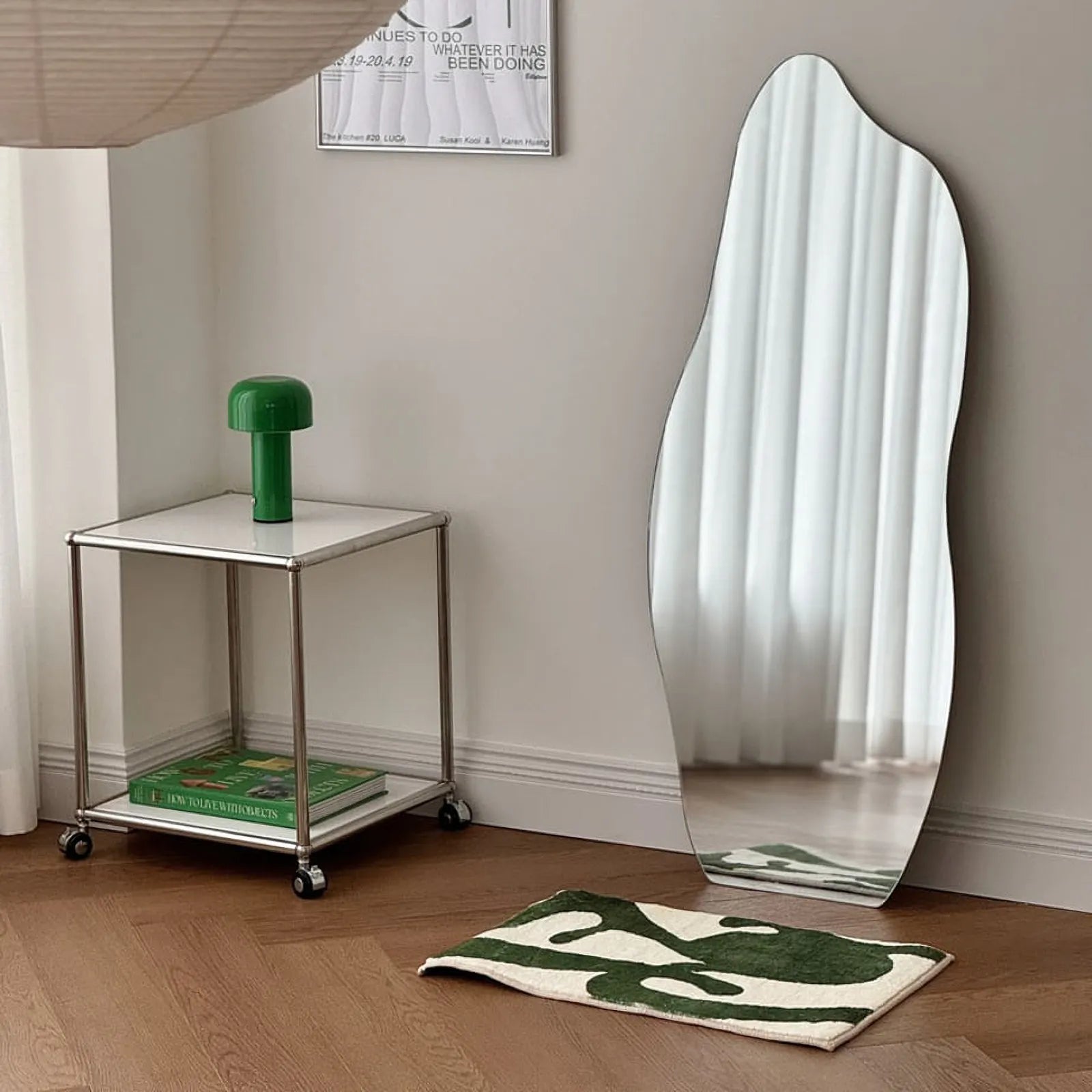 RoomDen green abstract art rug styling shot with a chrome table and green lamp.