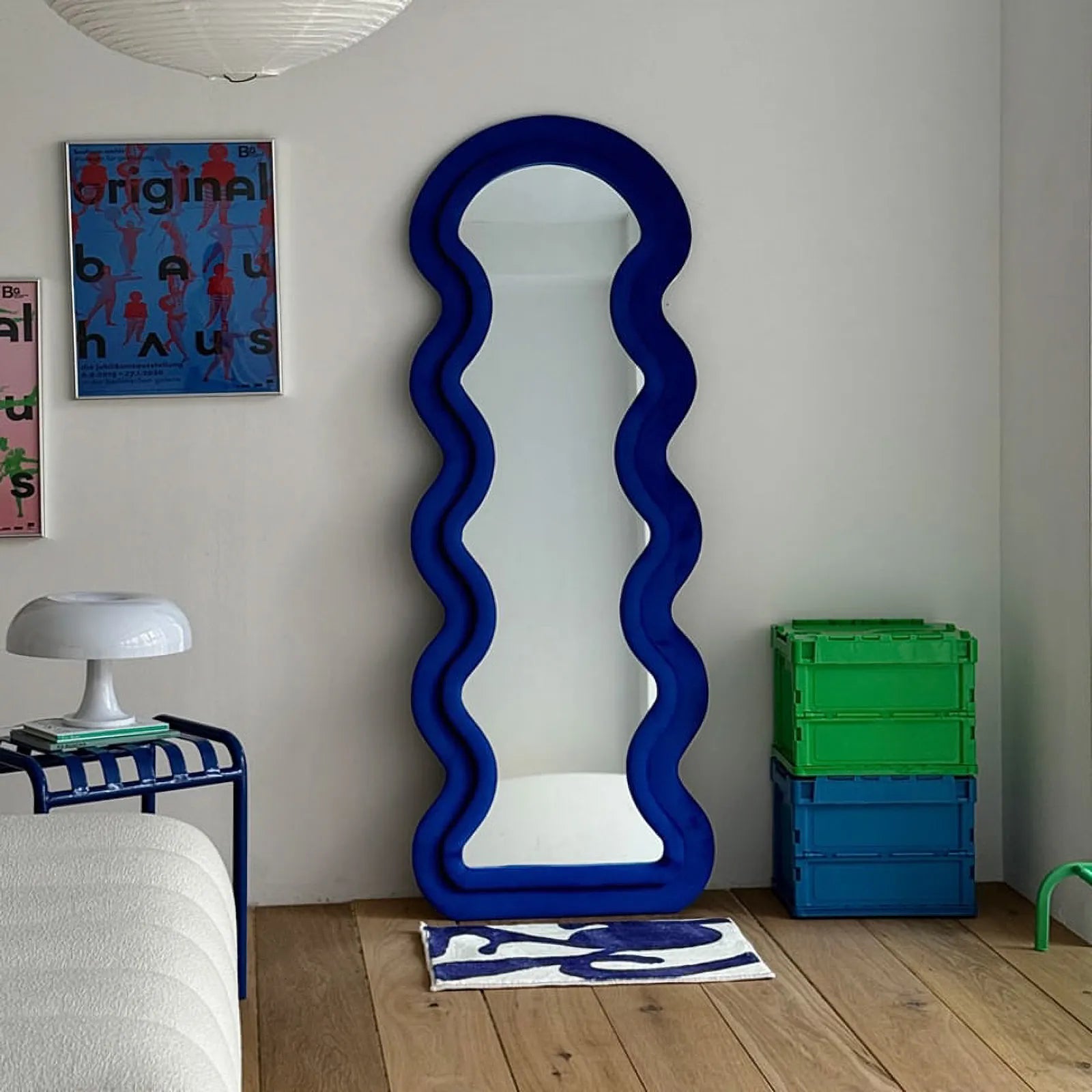 Full room shot showing the blue abstract rug with a tall blue wavy mirror and white sofa.
