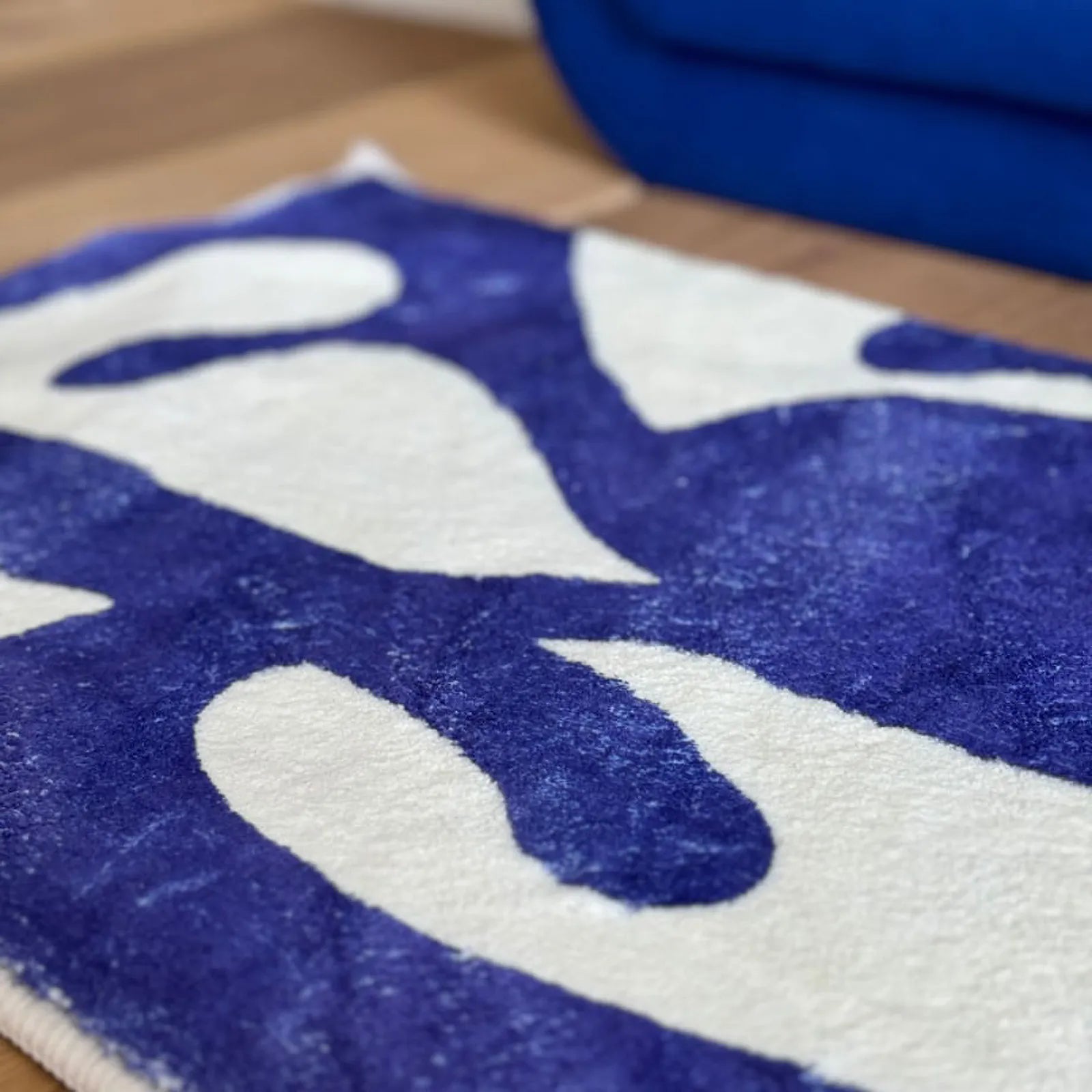 Close-up perspective of the blue organic shapes on the white tufted rug background.