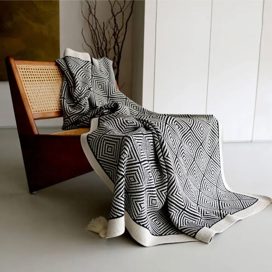 Black and white diamond knit fleece throw blanket draped over a wooden chair - RoomDen