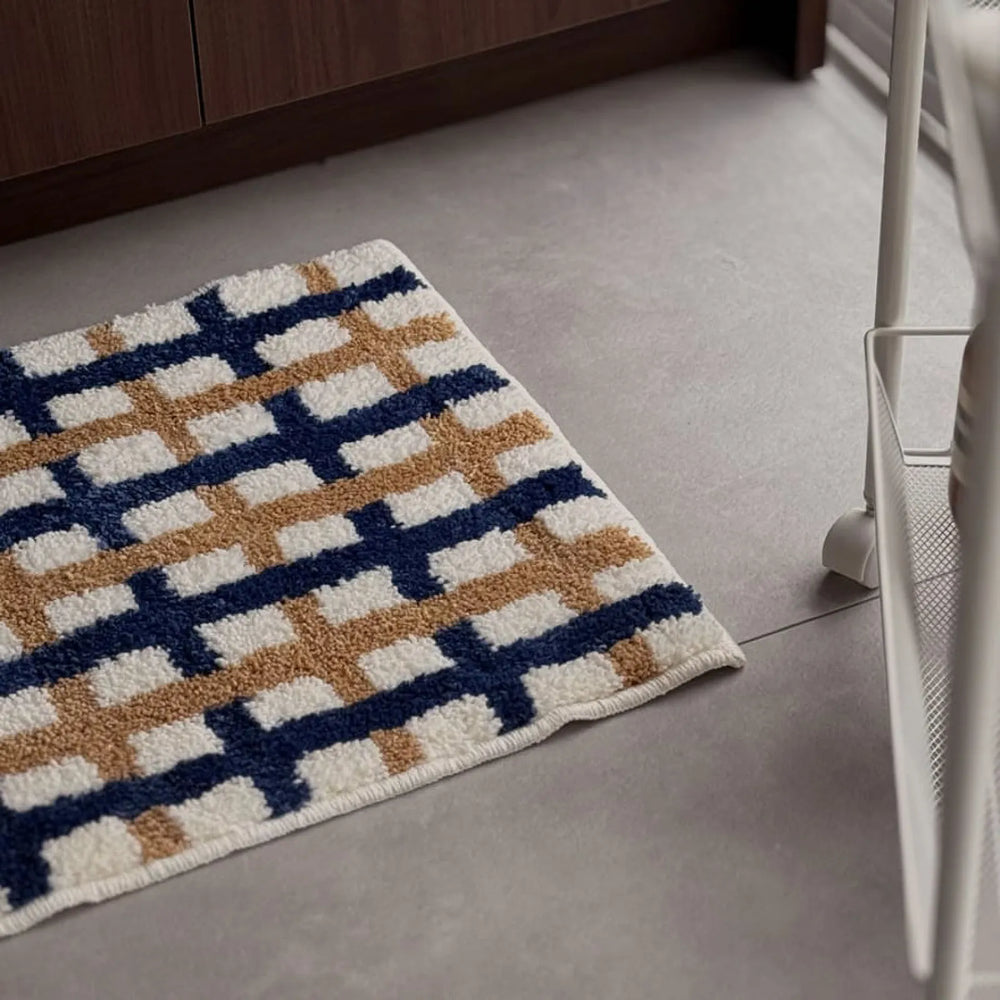 Angled view of navy and tan grid shaggy rug on grey floor near white cart - RoomDen