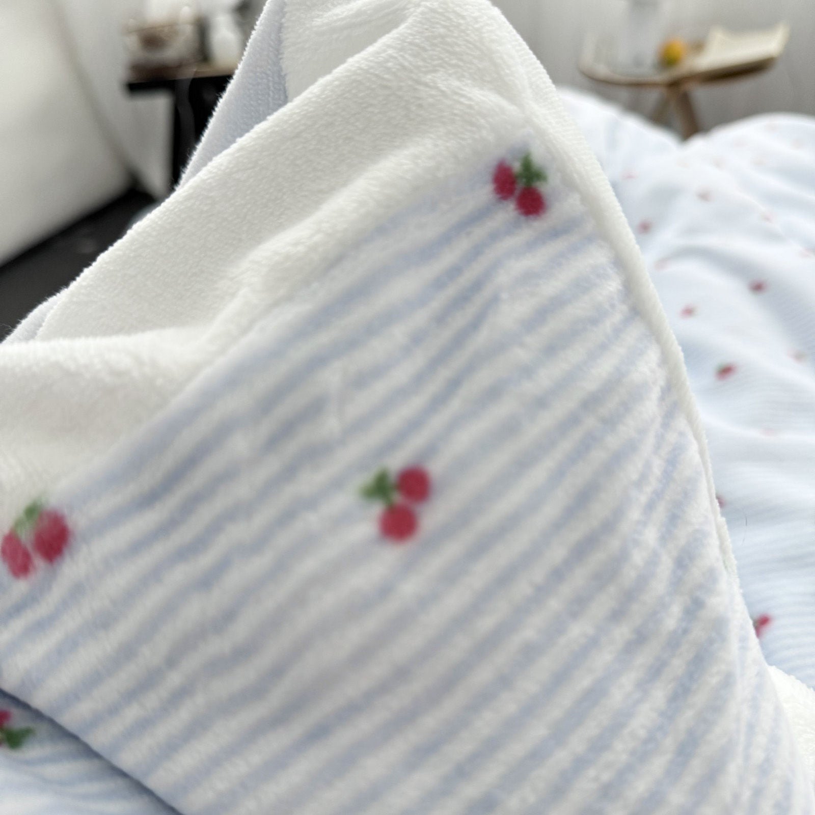Close up detail of tufted embroidered red cherry texture on blue striped fleece fabric. RoomDen.