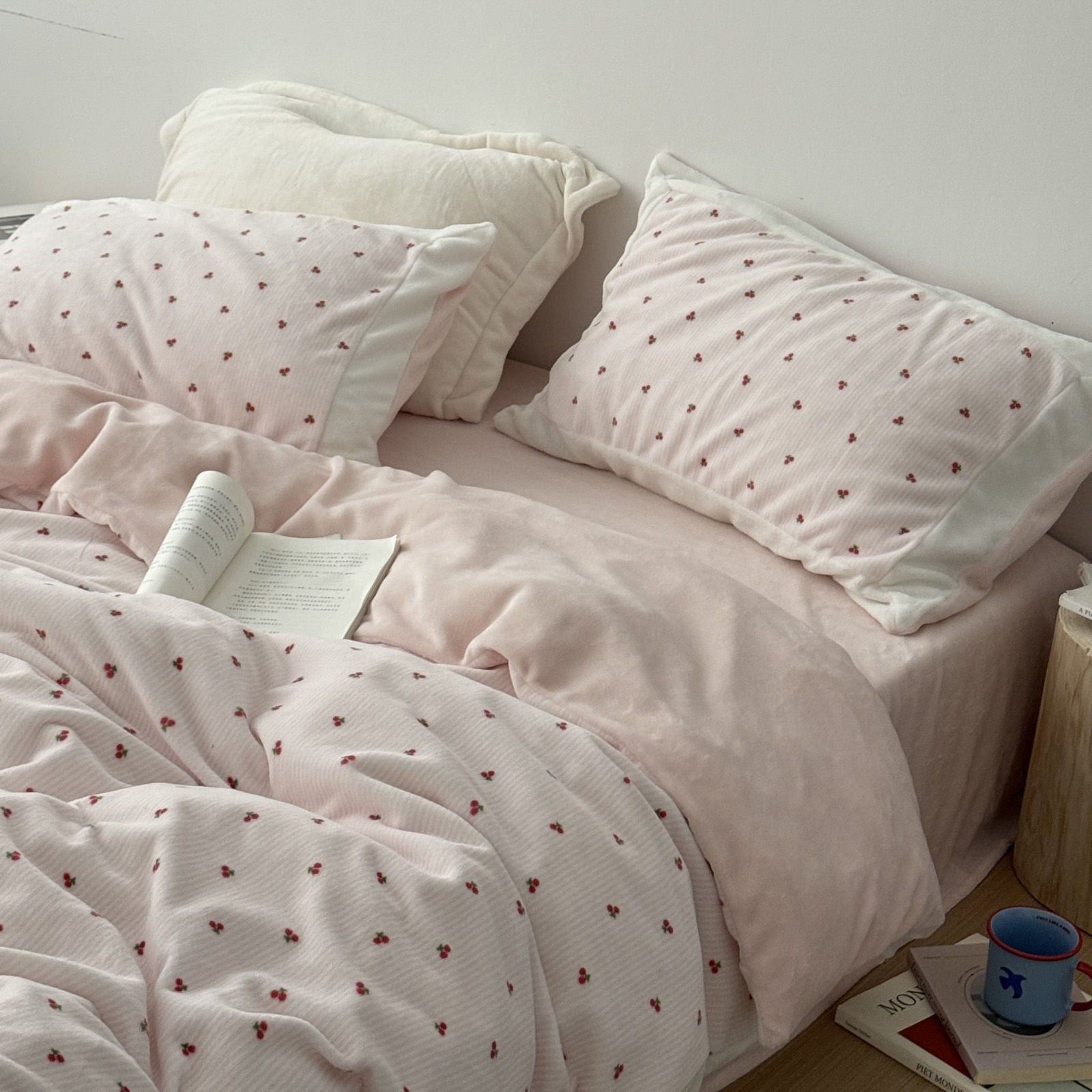 Full view of pink cherry fleece bedding on bed with wooden side table - RoomDen