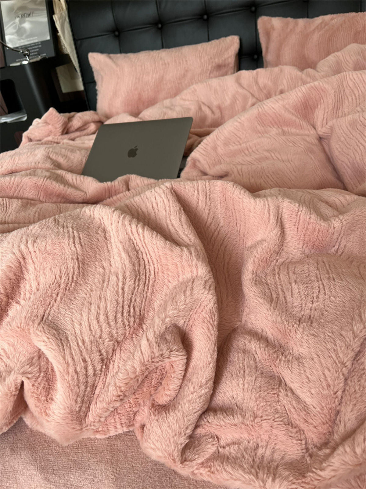 Pink plush bedding set with rippled texture and laptop on bed RoomDen