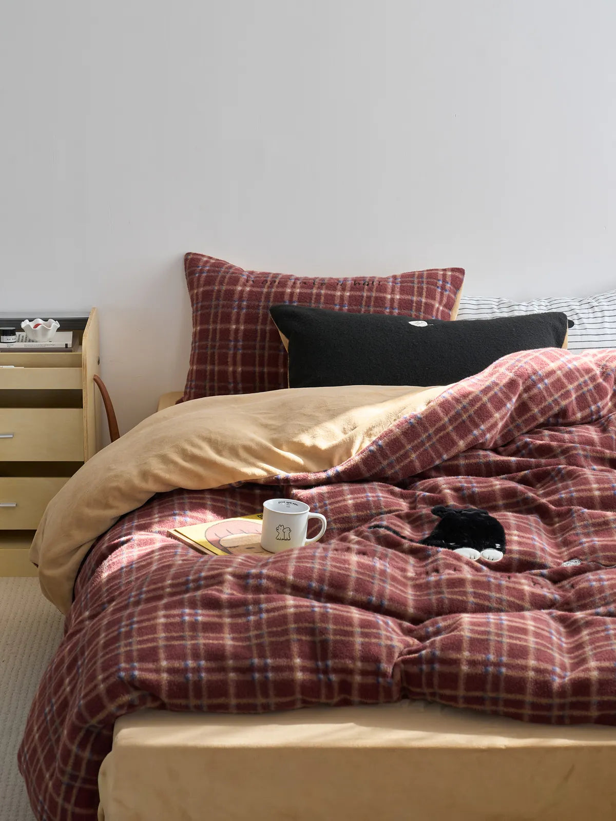 RoomDen red plaid flannel fleece bedding set styled on bed with black cat plush.