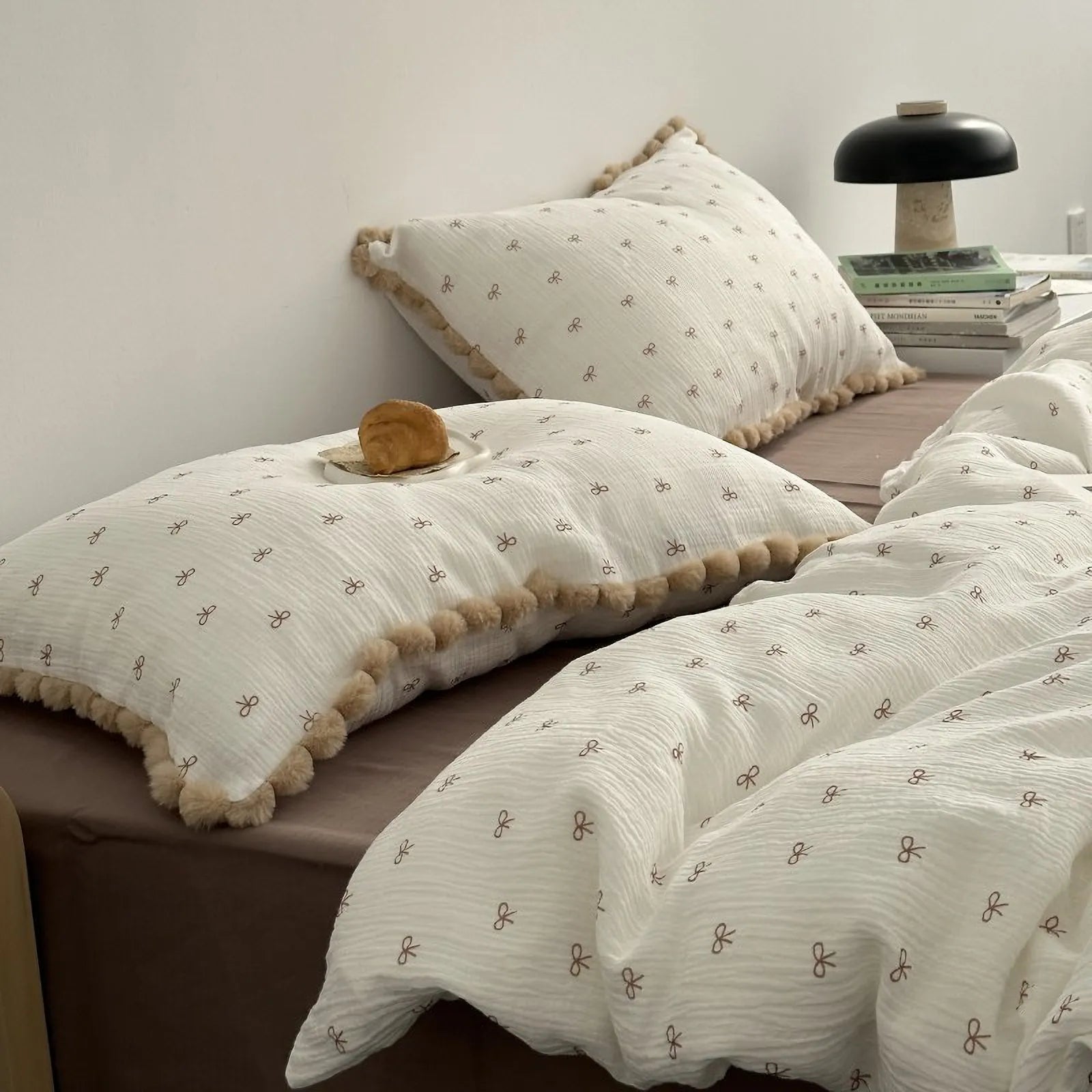 RoomDen soft washed cotton bedding set in cream with brown bow ties and pom pom trim, side view