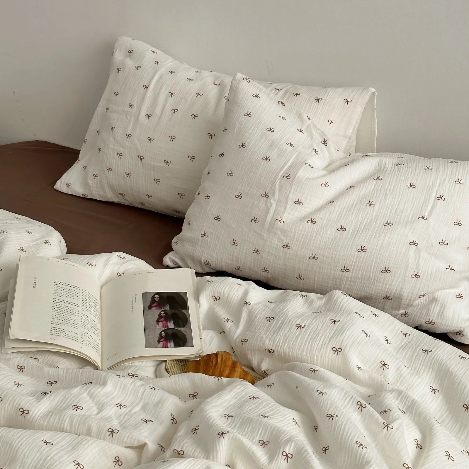 Lifestyle shot of RoomDen bedding with an open book, highlighting the cozy coquette aesthetic