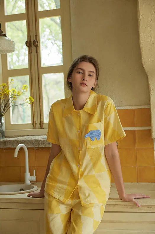 Woman wearing a soft sunny yellow checkered cotton pajama set in a warm kitchen setting – RoomDen