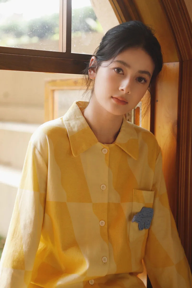 Woman wearing a soft sunny yellow checkered cotton pajama set by the window with warm natural light – RoomDen