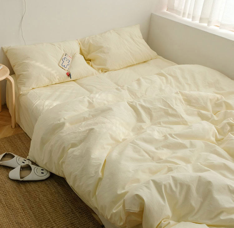 Beige washed cotton bedding set on a low platform bed with natural sunlight and cozy slippers beside - RoomDen