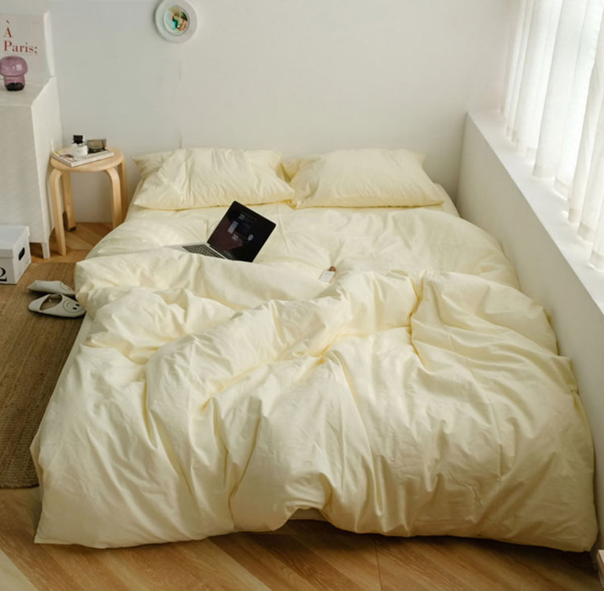 Minimalist beige washed cotton bedding set in a bright bedroom with wooden floor and white curtains - RoomDen