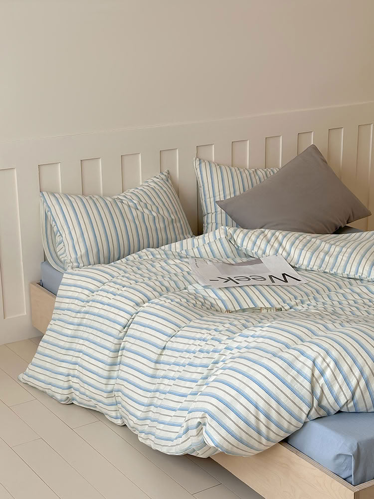 Blue striped washed cotton bedding set with striped and solid pillowcases on wooden bed – RoomDen