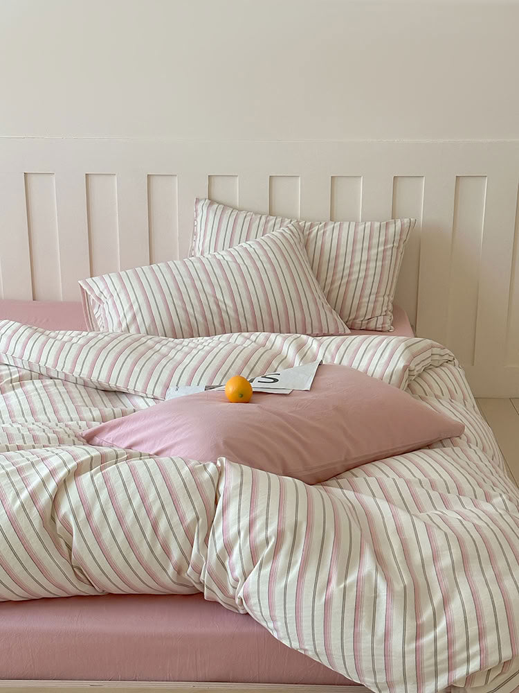 Pink striped washed cotton bedding set with striped and solid pillowcases on wooden bed – RoomDen