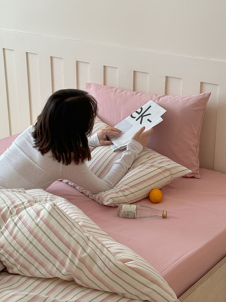Soft pink striped and solid pillowcase bedding styled in a light cozy room – RoomDen