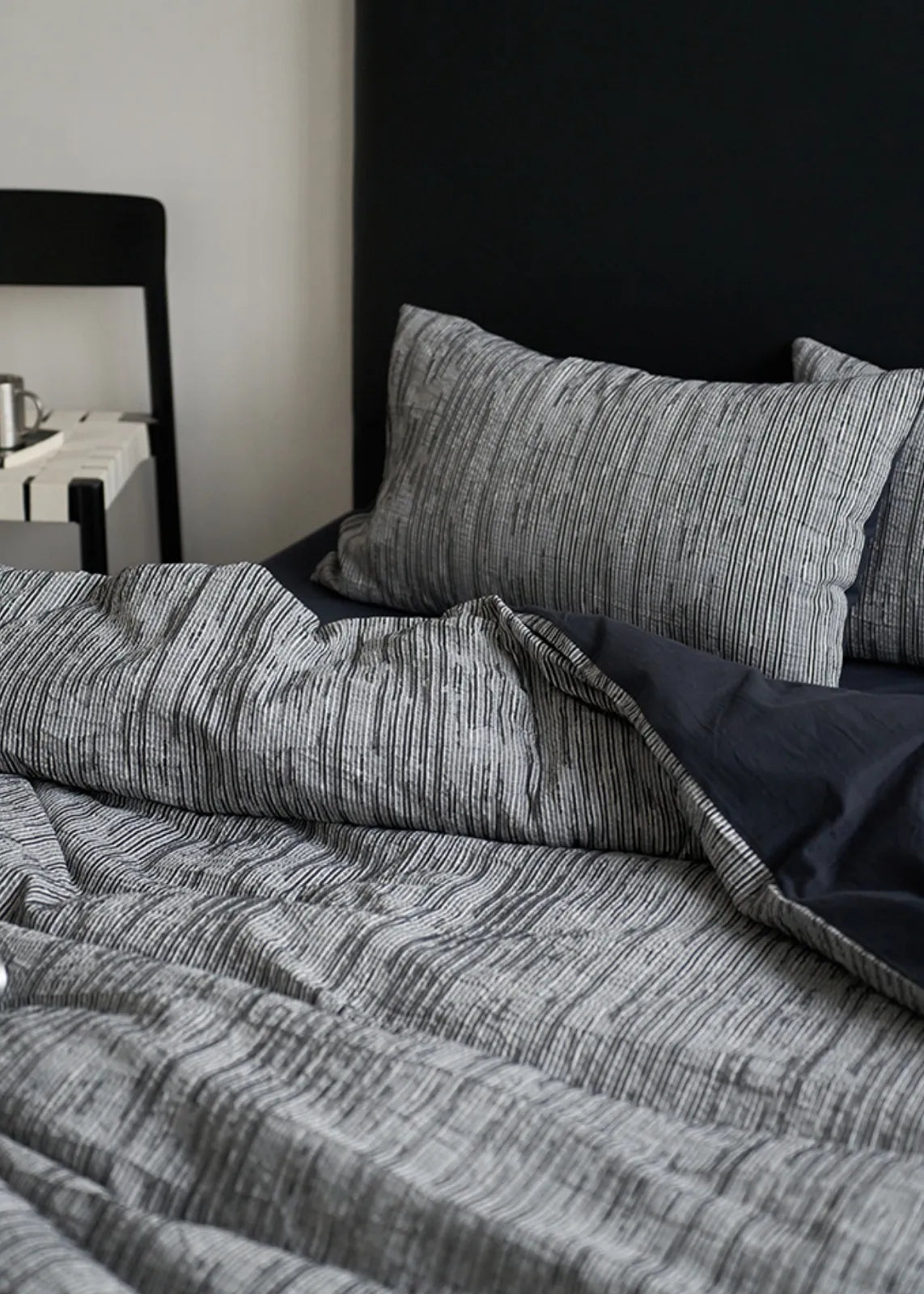 Close up texture of dark grey crinkled cotton duvet cover with light stripes RoomDen.